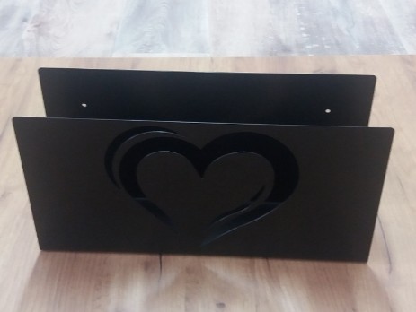 Metal newspaper holder on wall with a decorative heart motif